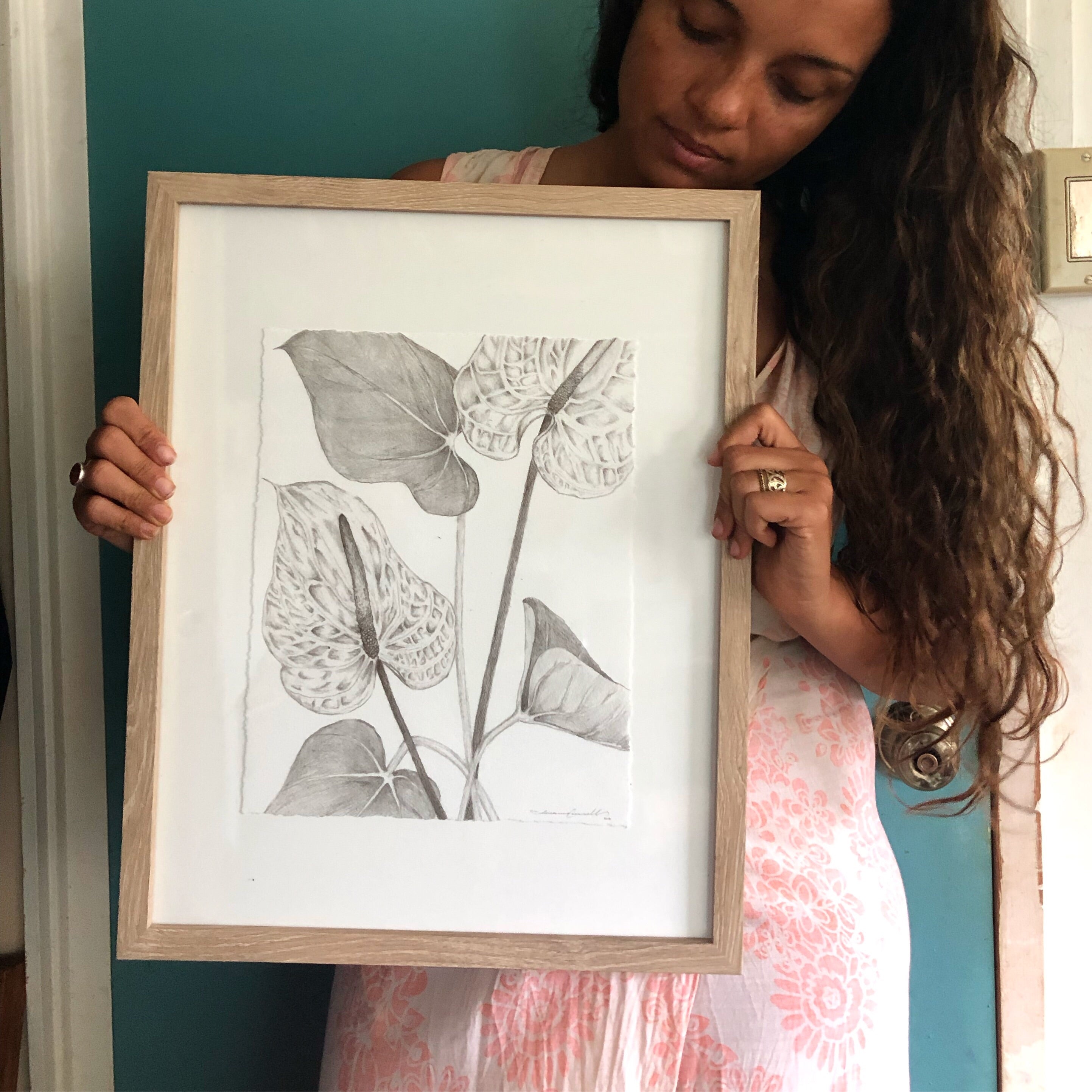 woman holding framed pencil drawing of anthuriums